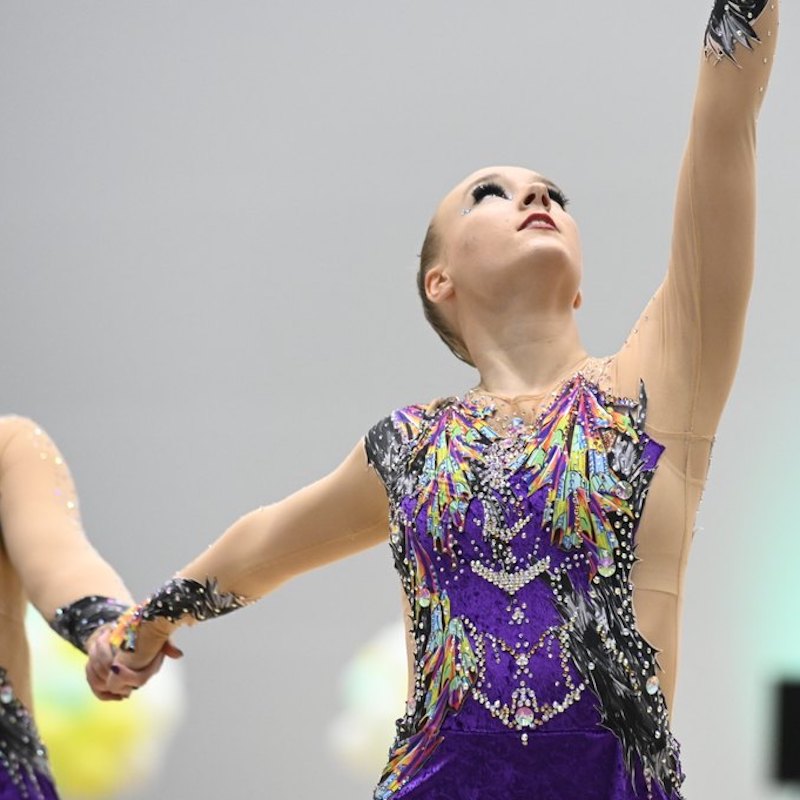 Voimistelija violetissa kilpailupuvussa.