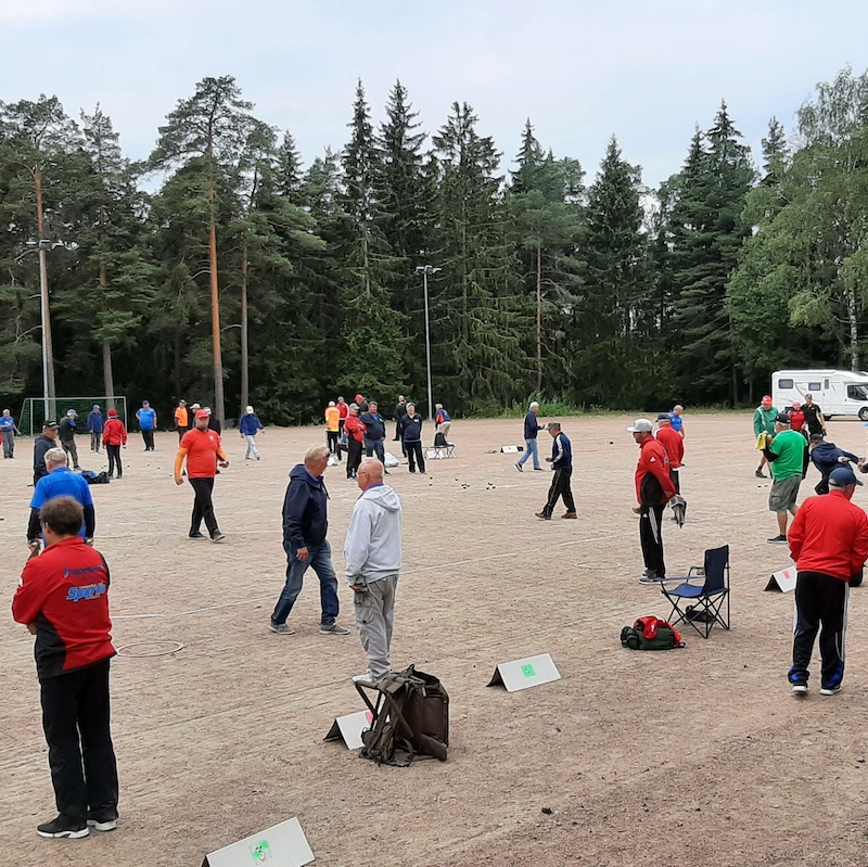 Petankkikilpailuista tilannekuva. Hiekkakentällä pelaajia kymmeniä pelaajia.