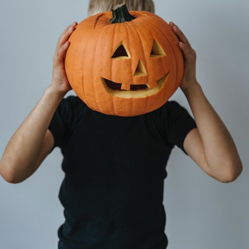 Halloween leiri. Lapsi pitää kurpitsaa naamansa edessä.