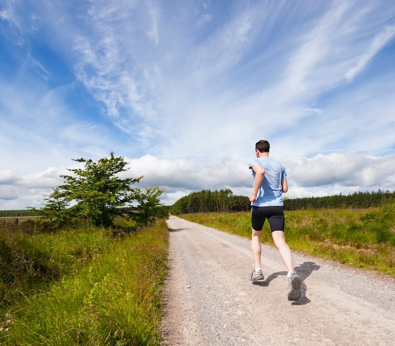 Kuvituskuva, jossa miesoletettu juoksee hiekkatietä poispäin. Taiavs on sininen ja hiekkatien molemmin puolin pellot.
