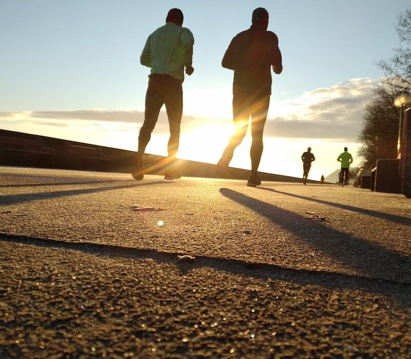 Neljä juoksijaa juoksee kohti auringonlaskua.