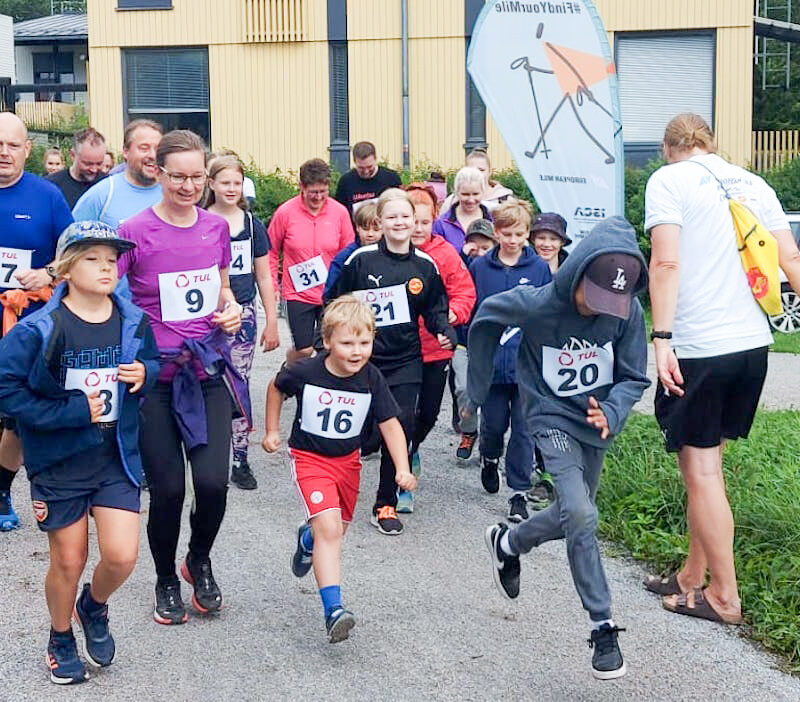 Valttimaili. Joukku ihmisiä on lähtenyt juoksemaan hiekkatietä. Kaikilla juoksijoilla numerolaput.