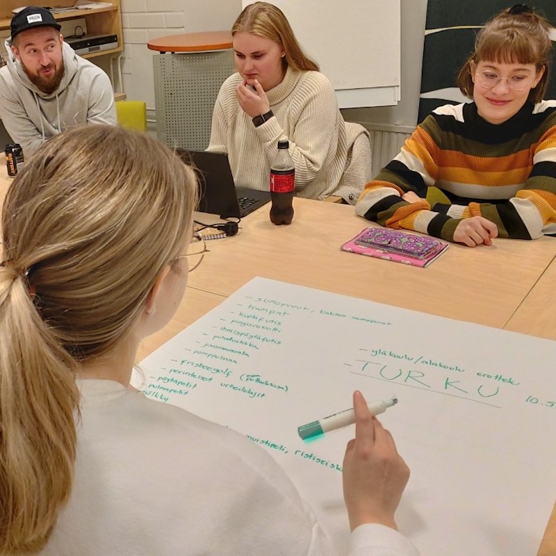 Nuoret päättäjät -koulutuksessa neljä nuorta hahmottaa paperille kehitysideoita pöydän ympärillä.
