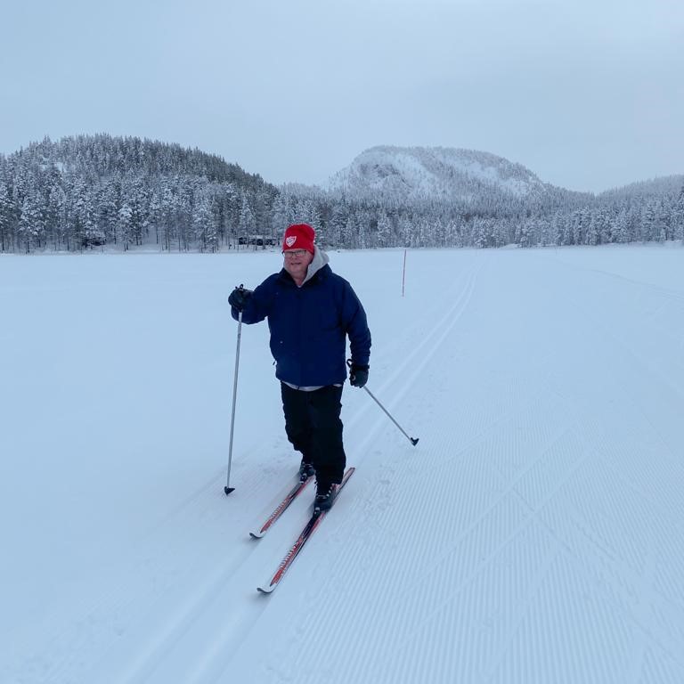 Mies hiihtää talvisessa maisemassa .