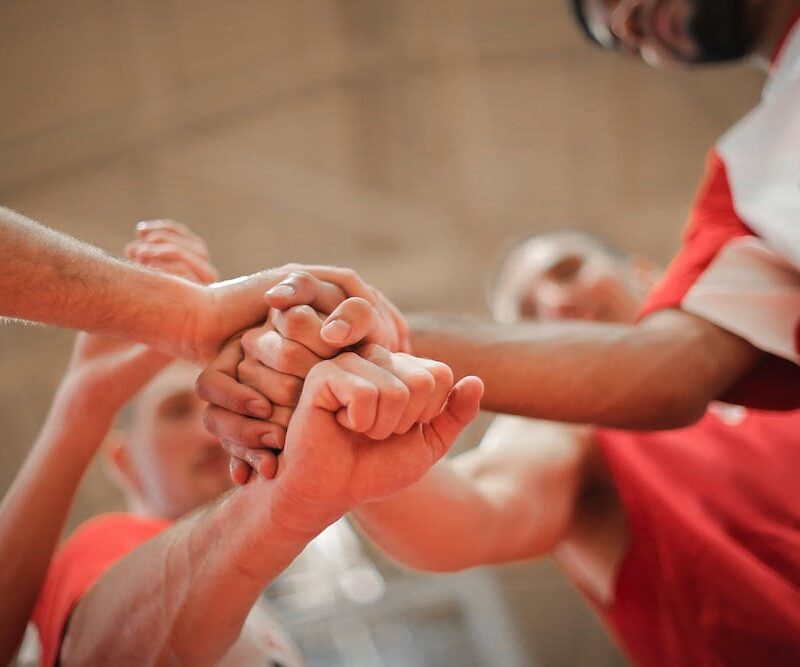 Urheilujoukkue viemässä kädet yhteen tsemppipiirissä.