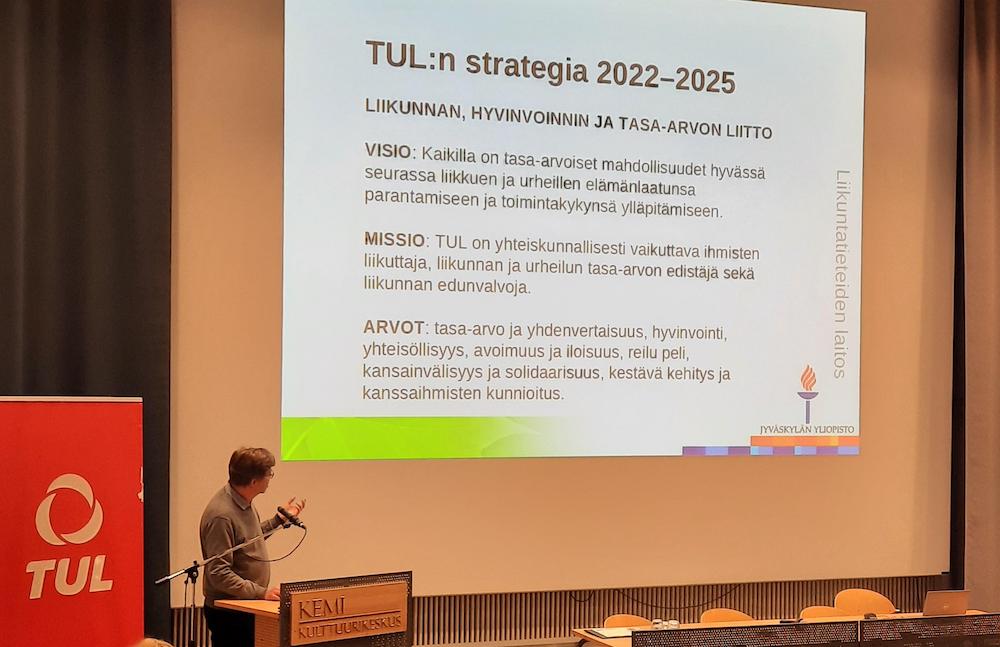 Hannu Itkonen luennoimassa, taustalla dia, jossa esitellään TUL:n strategia.