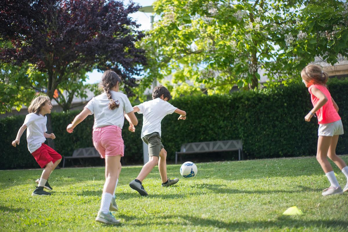 Lapsia pelaamassa jalkapalloa ulkona.